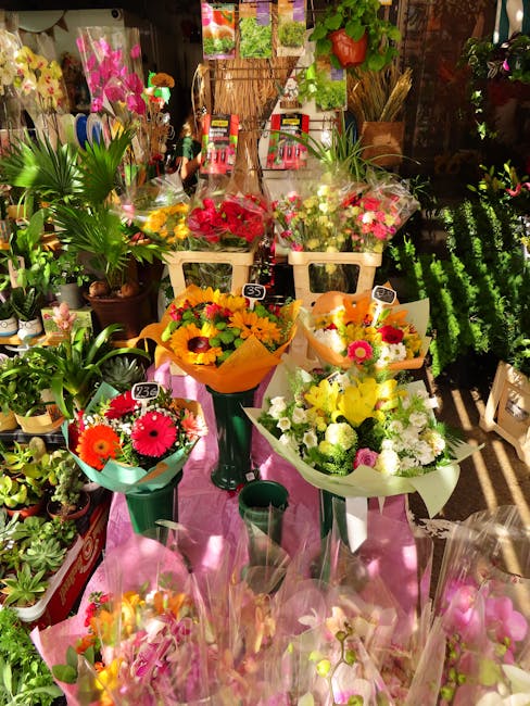 A vibrant floral display featuring an assortment of fresh flower bouquets arranged in various vibrant colours including reds, yellows, pinks, and whites. The bouquets are wrapped in bright, colorful p